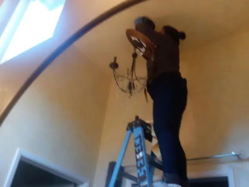 Electrician installing a chandelier in a State College residence